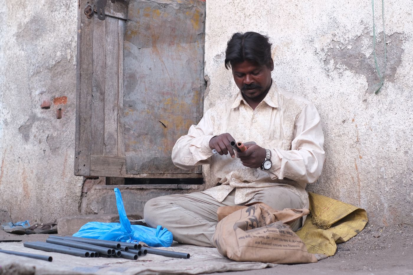 A tradesman preparing pipes outdoors in Rajkot, India